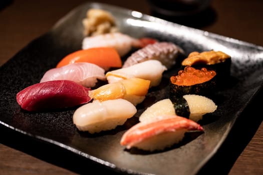 Assorted sushi set served on black tray.