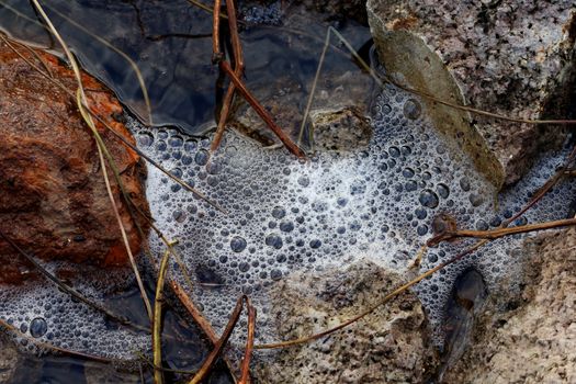 sponge on the rocky surface close up, waste water, dirty water pollution, white bubbles on the surface and stone