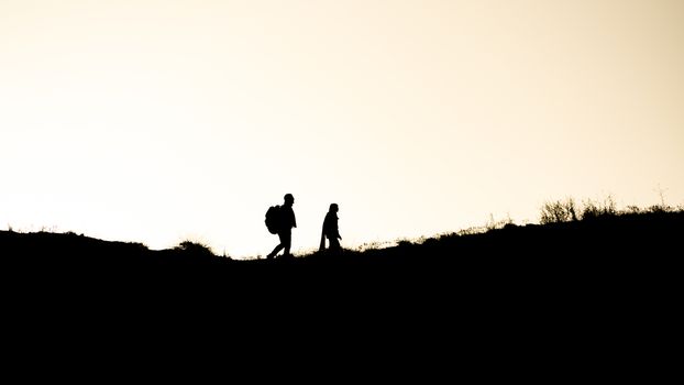 SIlhouette of a couple walking at sunset on a hill.