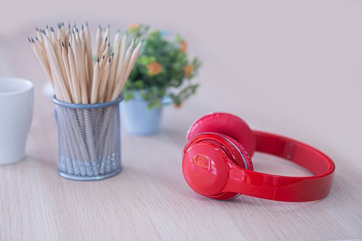 the red head phone and pencil case on white table