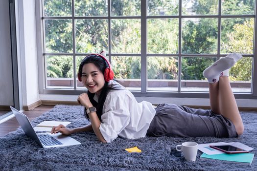 top view of young asian woman working with laptop computer in the living room. Work from home and study at home concept.