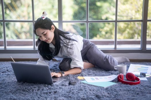 top view of young asian woman working with laptop computer in the living room. Work from home and study at home concept.