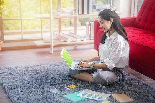 top view of young asian woman working with laptop computer in the living room. Work from home and study at home concept.