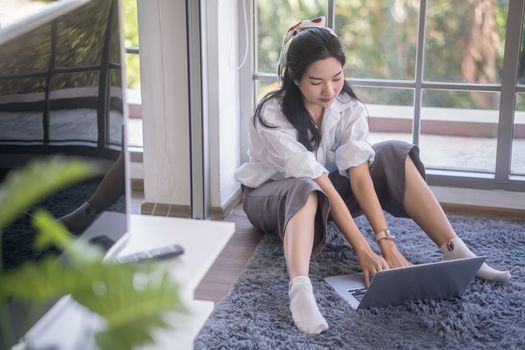 top view of young asian woman working with laptop computer in the living room. Work from home and study at home concept.