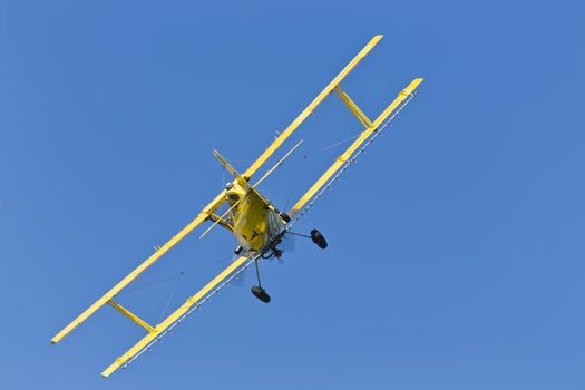A crop duster applies chemicals to a field of vegetation.