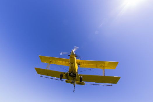 A crop duster applies chemicals to a field of vegetation.