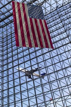 A commercial aircraft takes off from an international airport with an American flag in the foreground