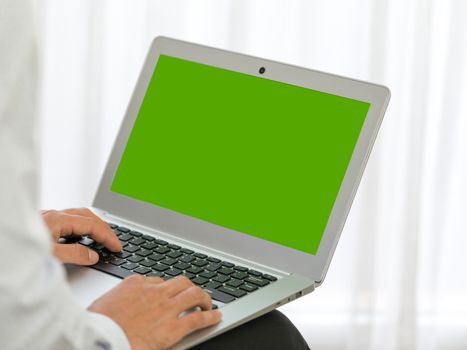 Business man hands typing on laptop computer with green screen. Close up