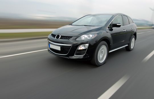 A panning shot of a speeding SUV