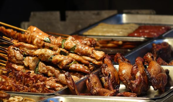 A street food stall in Taiwan offers grilled meat skewers and chicken legs