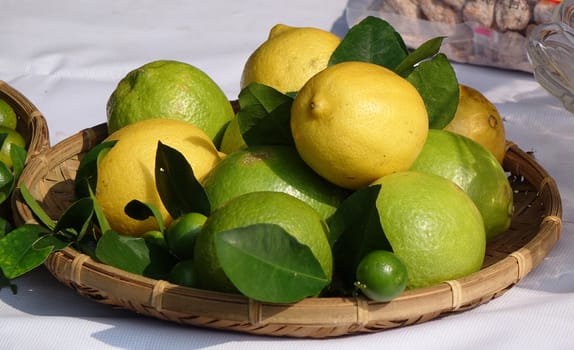Fresh lemons and limes in a traditional bamboo tray
