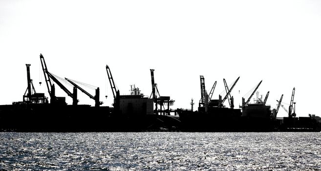 A row of loading cranes in Kaohsiung port seen in silhouette