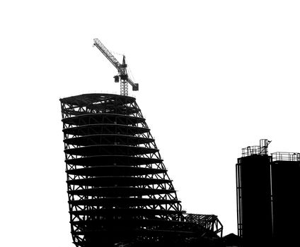 Construction site with crane and scaffolding seen as a silhouette