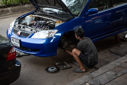 Bangkok, Thailand - February 1, 2020 : Unidentified car mechanic or serviceman disassembly and checking a disc brake and asbestos brake pads for fix and repair problem at car garage or repair shop