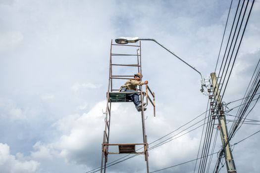 Bangkok, Thailand - June 26, 2016 : Unidentified electricians or handyman or worker risk working to install electric line on high pole by scaffolding on pickup truck at Bangkok Thailand.