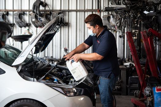 Bangkok, Thailand - April 4, 2020 : Unidentified car mechanic or serviceman cleaning the car engine after checking a car engine for fix and repair problem at car garage or repair shop