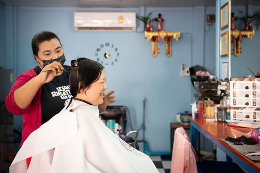 Bangkok, Thailand - February 2, 2020 : Unidentified asian woman hairdresser or hairstyle haircut a woman plump body customer in fashion hairstyle at barbershop