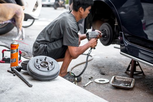 Bangkok, Thailand - February 15, 2020 : Unidentified car mechanic or serviceman disassembly and checking a disc brake and asbestos brake pads for fix and repair problem at car garage or repair shop