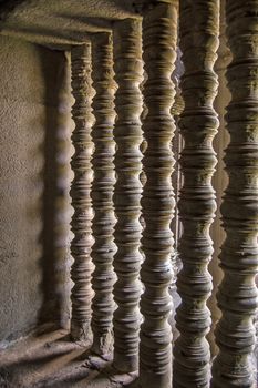 Detail of sunlight filtering through the turned stone bars of a window at the ancient Khmer temple of Angkor Wat, Siem Reap, Cambodia.