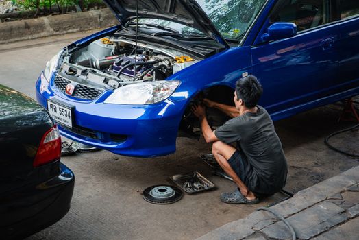 Bangkok, Thailand - February 1, 2020 : Unidentified car mechanic or serviceman disassembly and checking a disc brake and asbestos brake pads for fix and repair problem at car garage or repair shop
