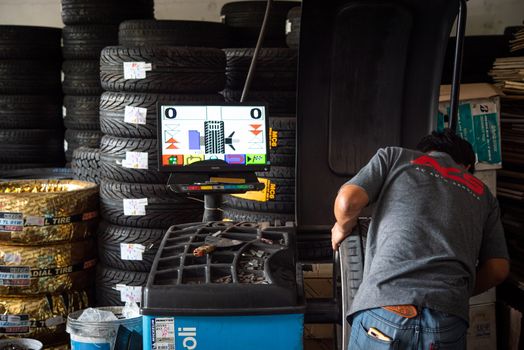 Bangkok, Thailand - April 4, 2020 : Unidentified car mechanic or serviceman wheel alignment and tire balance checking car wheel for fix and repair suspension problem at car garage or repair shop