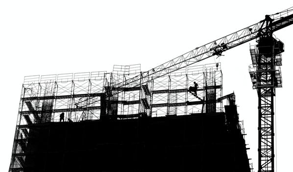 Construction site with crane and scaffolding seen as a silhouette