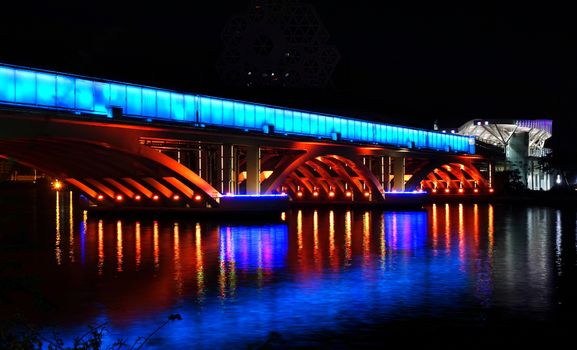 Evening view of the Love River with the illuminated light rail bridge and the True Love Pier station.