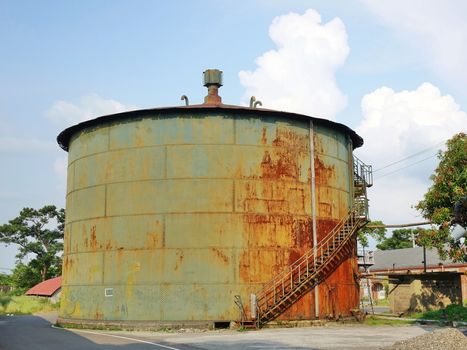 A large rusting storage tank at a vintage industrial facility