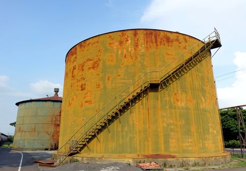 Two large rusting storage tanks at a vintage industrial facility
