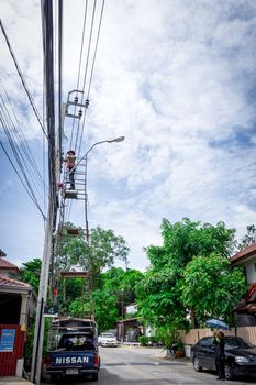 Bangkok, Thailand - June 26, 2016 : Unidentified electricians or handyman or worker risk working to install electric line on high pole by scaffolding on pickup truck at Bangkok Thailand.