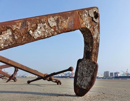 Large rusty buoy anchor encrusted with barnacles
