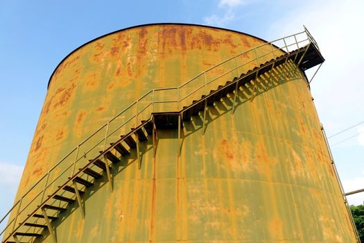 A large rusting storage tank at a vintage industrial facility