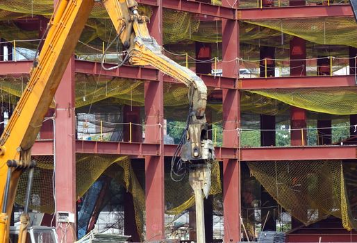 A hydraulic pile driver sinks a large support post into the river bed for bridge construction.
