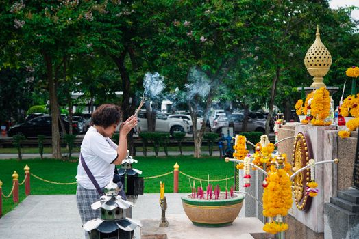 Bangkok, Thailand - August 24, 2017 : Unidentified Thai buddhism people in buddhist pray for benefaction worship by incense and garland to Buddha or spirit-house at shrine or Thai temple (Wat Thai)