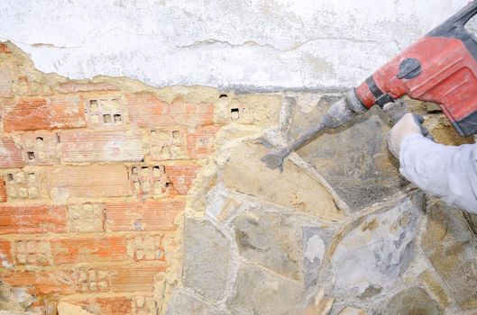 Mason with electric hammer in rehabilitation work.
