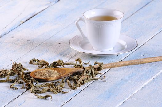 Cup of chamomile and herbs on wooden table in the kitchen.