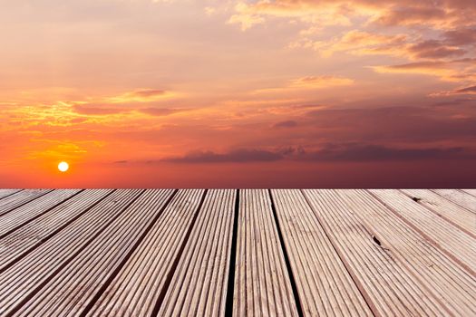 wooden table top with the colorful dramatic sky with cloud at sunset