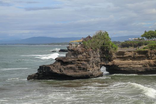 Batu Bolong beach which has an tourism attraction spot close to Tanah Lot temple. Huge hole in rock cliff below Pura Batu Bolong temple. Hindu Temple on the Beatiful Rock in the morning light, Bali.