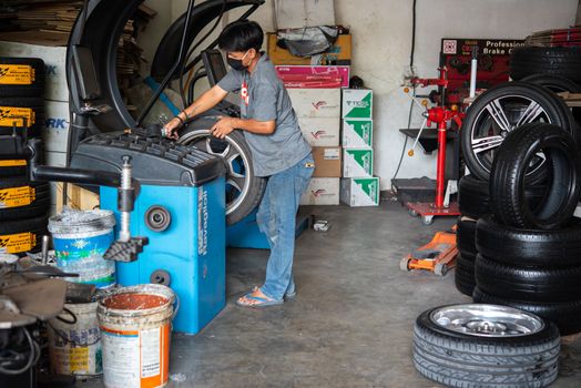 Bangkok, Thailand - April 4, 2020 : Unidentified car mechanic or serviceman wheel alignment and tire balance checking car wheel for fix and repair suspension problem at car garage or repair shop