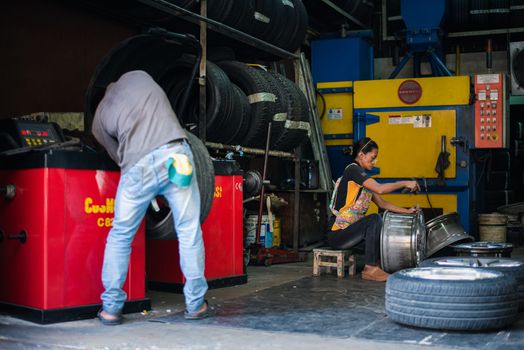 Bangkok, Thailand - September 1, 2017 : Unidentified car mechanic or serviceman disassembly and checking a car alloy chrome wheel for fix and repair suspension problem at car garage or repair shop