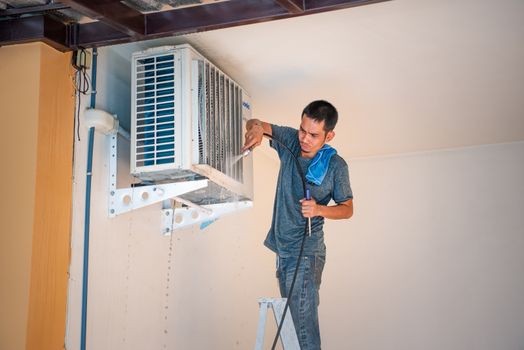 Bangkok, Thailand - January 12, 2020 : Unidentified worker to cleaning coil cooler of air conditioner by water for clean a dust on the wall in customer home when maintenance service