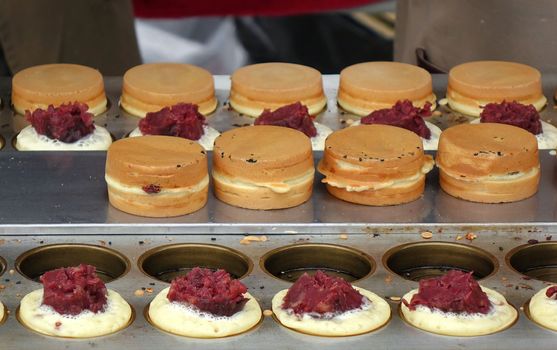  An outdoor vendor prepares sweet red bean cakes, a popular Chinese snack.