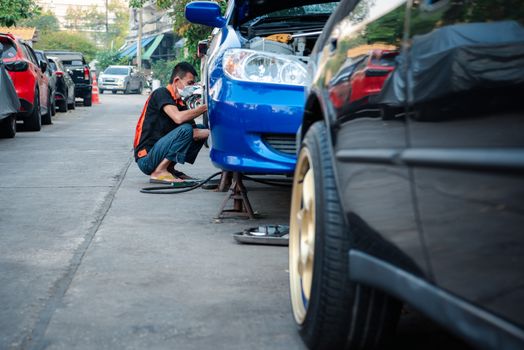 Bangkok, Thailand - February 1, 2020 : Unidentified car mechanic or serviceman disassembly and checking a disc brake and asbestos brake pads for fix and repair problem at car garage or repair shop