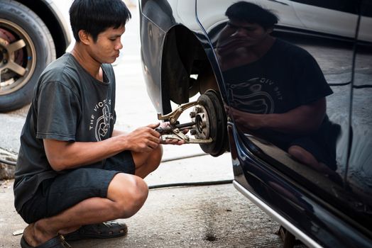 Bangkok, Thailand - February 15, 2020 : Unidentified car mechanic or serviceman disassembly and checking a disc brake and asbestos brake pads for fix and repair problem at car garage or repair shop