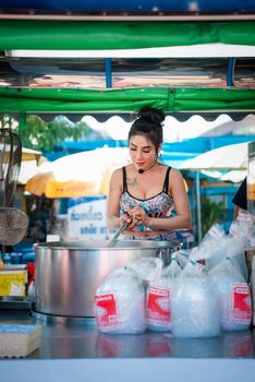 Samut Sakorn, Thailand - February 15, 2020 : Unidentified Asian sexy woman chef cooking a noodle soup with meat ball (kauy-tiew) for sale at Thai street food market or restaurant in Thailand