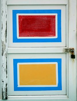 An old wooden door with red amd yellow painted rectangles
