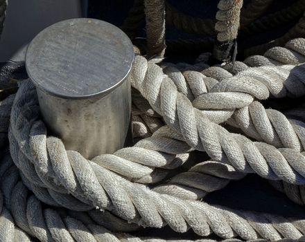 A steel mooring post with a thick rope wrapped around it
