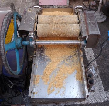 A market stall uses a hand-operated vintage peanut crusher to make peanut candy