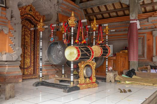 Musical instruments in a Hindu temple on Bali island, Indonesia. Drums and gongs suspended on load-bearing wooden ornate constructions. Musical instruments used in ceremonies.
