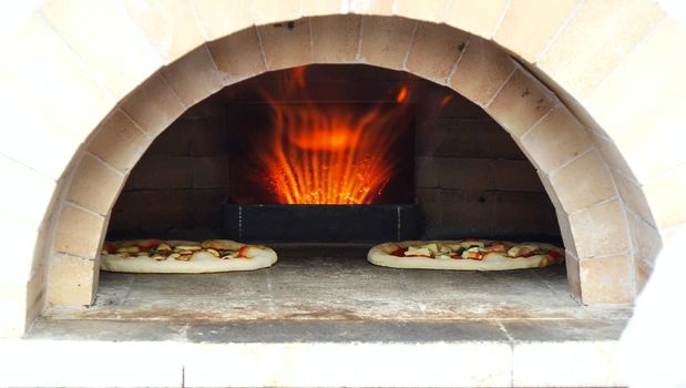 Pizza margherita with tomatoes, cheese and fresh basil is baking in the oven